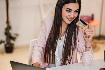 Young adult woman doing online shopping, e-shopping satisfied entrepreneur making online payment...