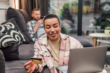 Holiday shopping online young person woman purchasing web shop, entrepreneur pays using laptop, happy person girl is enjoying buying gifts and sitting on floor with her laptop at home.