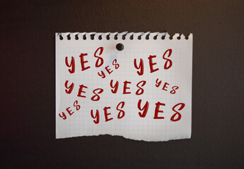 Paper note with YES written on black slate board