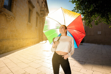 caucasian brunette young woman holding a colorful umbrella in urban city road
