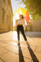 Vertical smiling woman with a rainbow umbrella outdoors