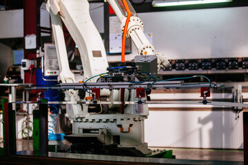 Robotic arm working with metal sheet at hydraulic bending machine