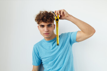 handsome guy yardstick in hand in blue t-shirts isolated background