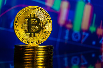 Bitcoin coin standing on stack of coins with trading chart background. Future and virtual money crypto currency