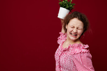 cheerful girl with flower pot posing emotions red background unaltered