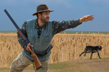 Hunter man in camouflage with a gun during the hunt in search of wild birds or game. Autumn hunting...