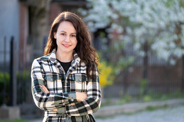 Fototapeta premium Portrait of pretty young woman smiling happily relaxing outdoors on spring sunny day
