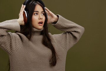 woman in a sweater listening to music with headphones fun studio model