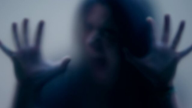 Defocused shot of Woman leaning on matte glass horror concept