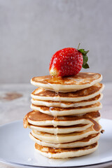 pancakes with honey and strawberries lies on a plate