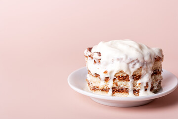 round piece of tiramisu with dripping cream on a white plate, close up with copy space