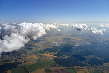 Aerial view from airplane window at high altitude of earth covered with puffy cumulus clouds...