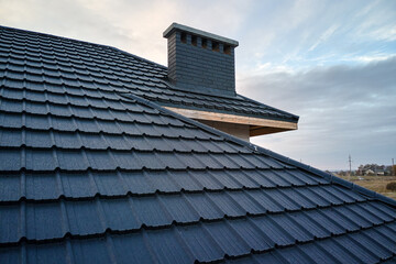Closeup of house roof top covered with metallic shingles.Tiled covering of building © bilanol