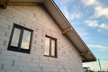 Unfinished house with aerated lightweight concrete walls and wooden roof frame covered with metallic tiles under construction