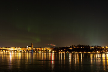 Northern lights, or Aurora Borealis, over Stockholm city skyline on a cold winter night with frozen water. Night view of S&ouml;dermalm in Stockholm, Sweden. Photo taken February 10, 2022.