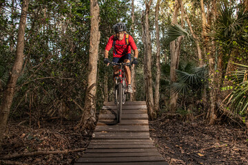 man riding a mountain bike on a trail with wood features