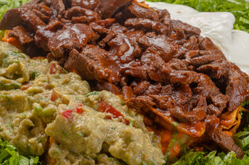 filet mignon in strips with sauce served with guacamole and curds and chopped lettuce