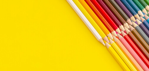 Colored pencils on yellow background. Top view with copy space. Flat lay. Back to school concept.