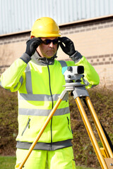 Site engineer checking levels of the road using autolevel