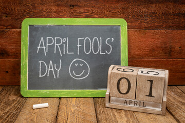April Fools' Day - white chalk handwriting on a vintage slate blackboard with wooden calendar