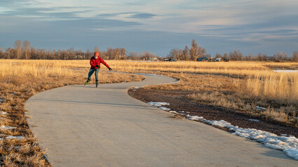 senior male is inline skating on a paved bike trail at sunset in northern Colorado, fall or winter...
