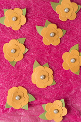 dainty artificial flowers with knock-off pearls arranged on a hot pink tissue paper surface