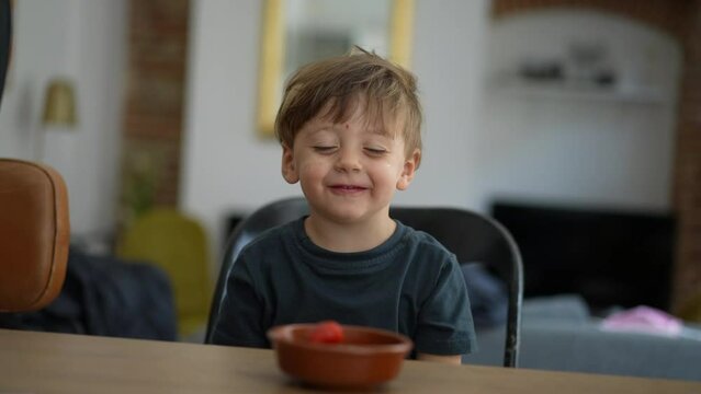 Happy small boy eating fruits from bowl smiling healthy snack