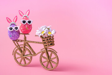 Easter composition on a pink background, an egg with rabbit ears and sunglasses, closeup with copy space