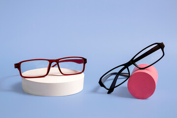 Classic glasses on a natural stone podium on a blue background. Optics. Closeup with copy space