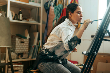 Young artist paints a picture with oil paints in a creative workshop on canvas