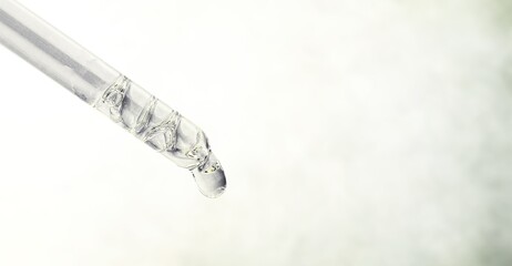 Cosmetic pipette with essential oil dropping, serum with peptides, hyaluronic acid on background....