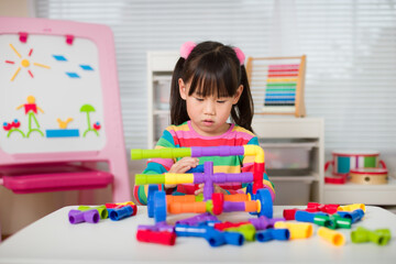 young girl playing water pipe construsction toy at home