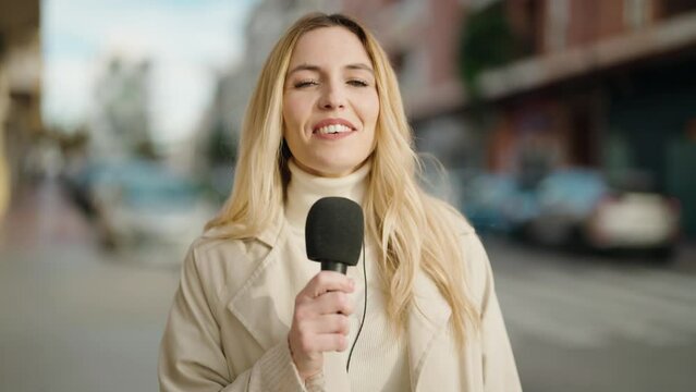 Young Blonde Woman Journalist Speaking Using Microphone At Street