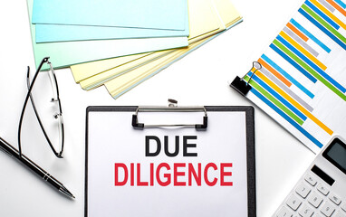 DUE DILIGENCE text on paper sheet with chart,color paper and calculator
