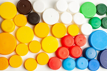 Colored plastic caps from bottles of water isolated on a white background. Close-up, top view. Recycling used plastic - a solution to the problem of plastic contamination.