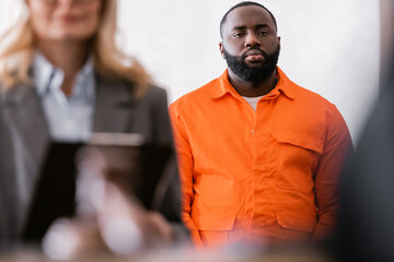 african american man in orange jail uniform near advocate on blurred foreground