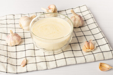 Lebanese garlic sauce Toum on a white table. Universal garlic sauce as an alternative to mayonnaise. Pairs well with all dishes
