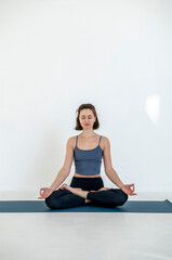Fototapeta premium Portrait of happy young caucasian woman exercising yoga. Healthy lifestyle. Woman meditating at home.