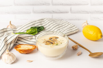 garlic soup puree. Bowl of creamy fried mushroom soup with garlic bread and fresh parsley on white table