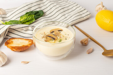 garlic soup puree. Bowl of creamy fried mushroom soup with garlic bread and fresh parsley on white table