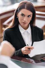 brunette prosecutor looking at blurred judge while holding lawsuit in court