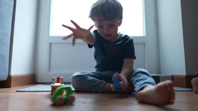 Little boy plays with traditional wooden car toys at home floor