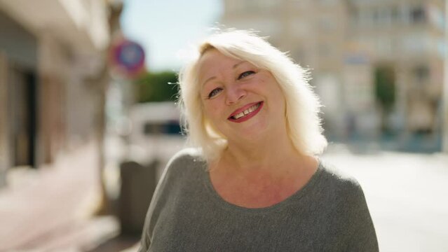 Middle age blonde woman smiling confident standing at street