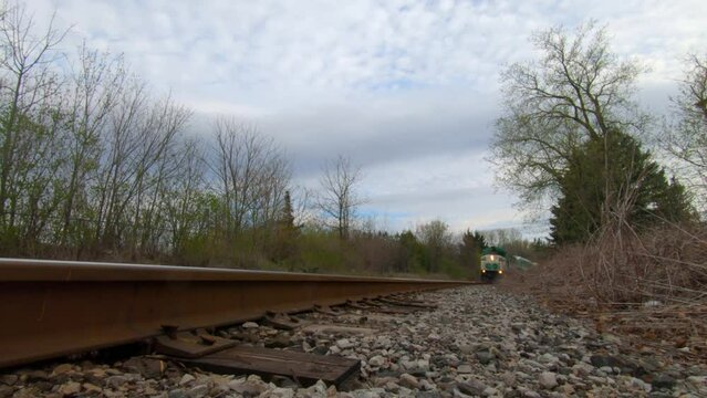 GO Train passing by over camera on the tracks in the suburban landscape.