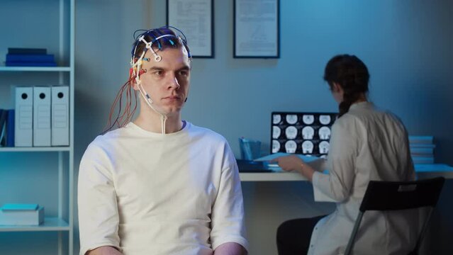 Man wearing EEG topographer for examining brain, doctor making electrogram of scalp activity. Researching of brain work using electroencephalography headset.