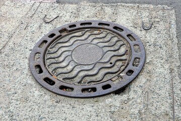 one brown closed iron manhole laying on the road in concrete