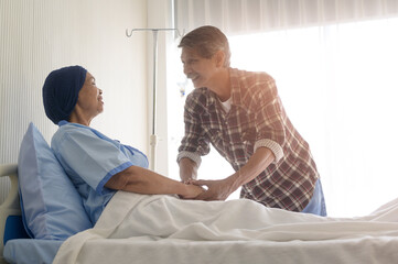 Senior man visiting cancer patient woman wearing head scarf at hospital, health care and medical concept