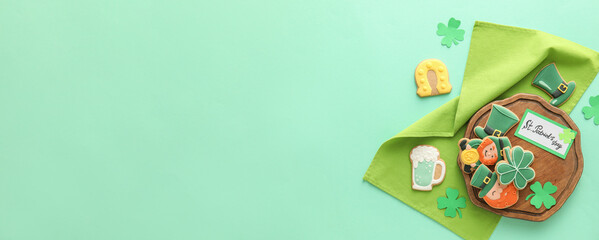 Tasty gingerbread cookies for St. Patrick's Day celebration on color background with space for text