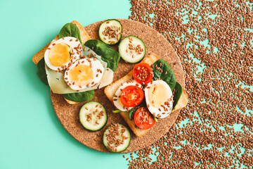 Board with tasty toasts and flax seeds on color background