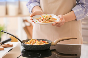 Woman with plate of cajun chicken pasta in kitchen